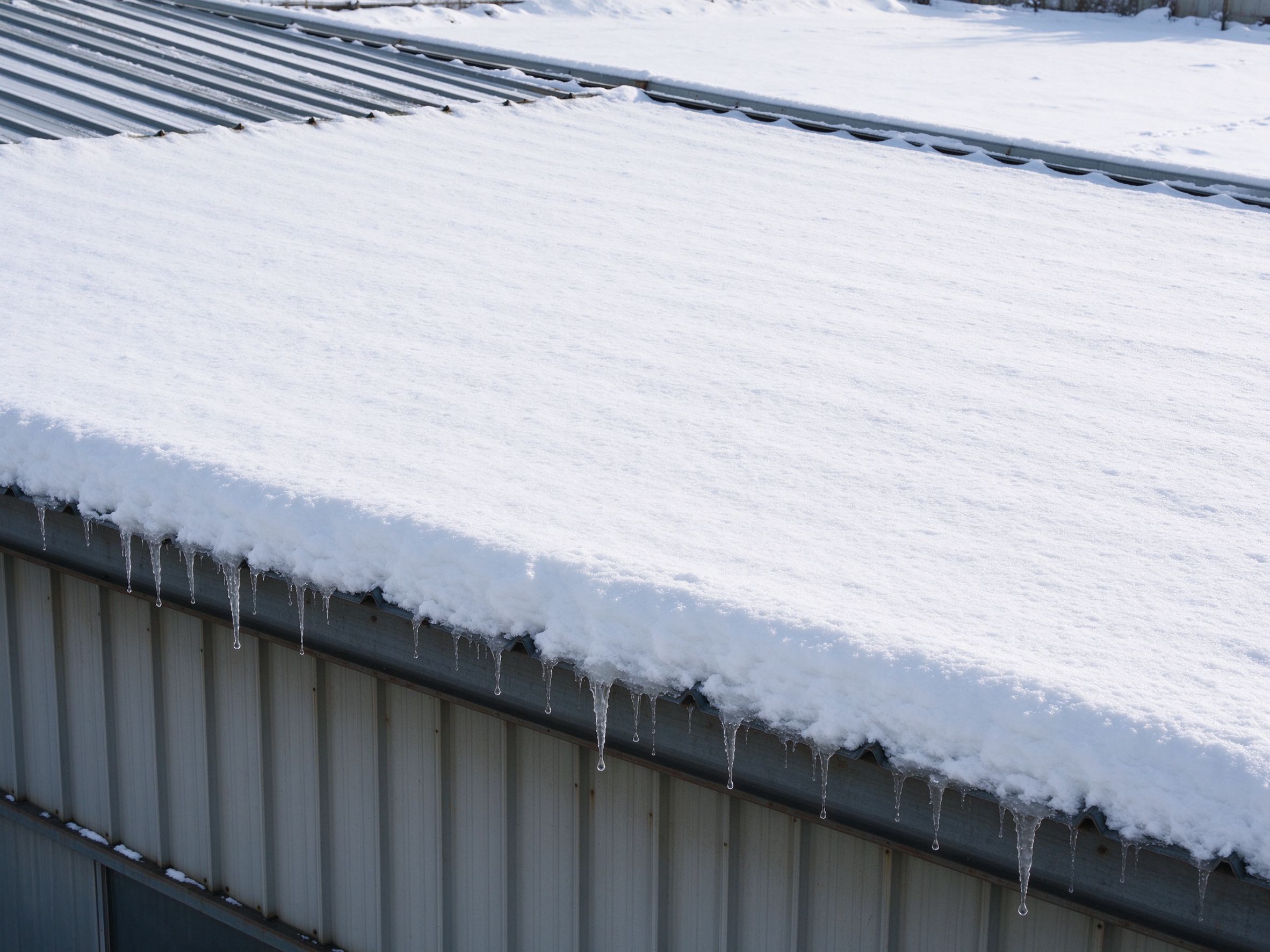 Roof of a steel building with snow accumulation (illustrative concept image)