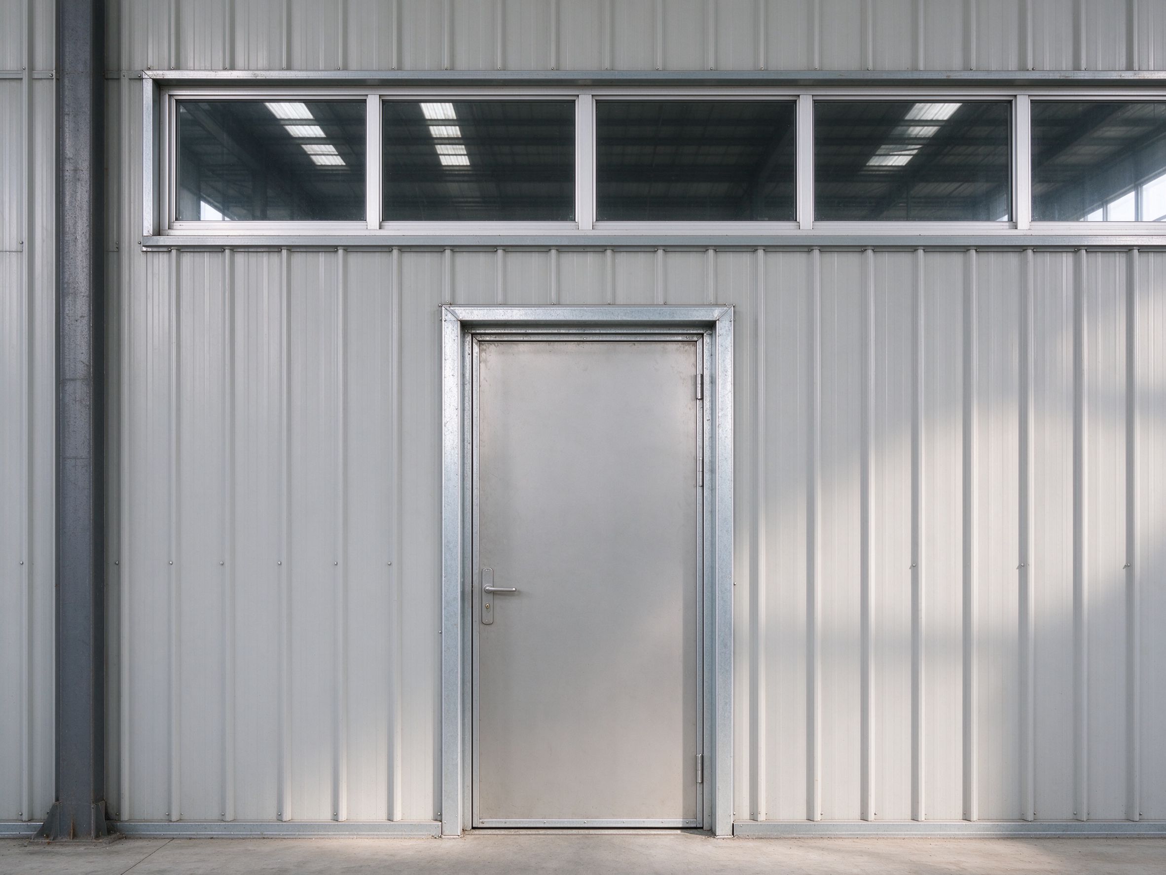 Personnel door and window openings on a steel building wall (illustrative concept image)