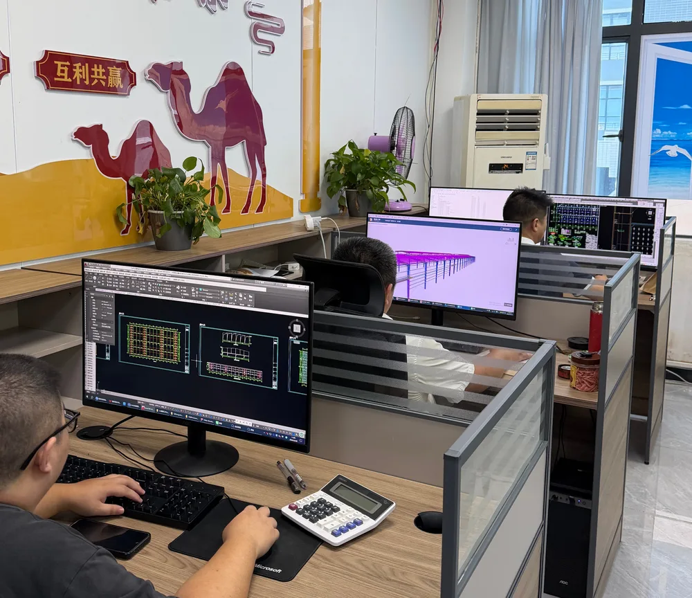 Design office team coordinating drawings at CAD workstations before fabrication